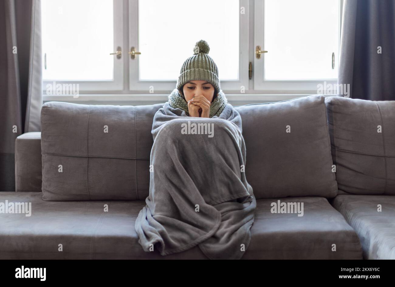 Kaltes Zuhause. Eine Frau, Die Mit Einer Decke Bedeckt War, Die Auf Der Couch Im Wohnzimmer Eingefroren War Stockfoto