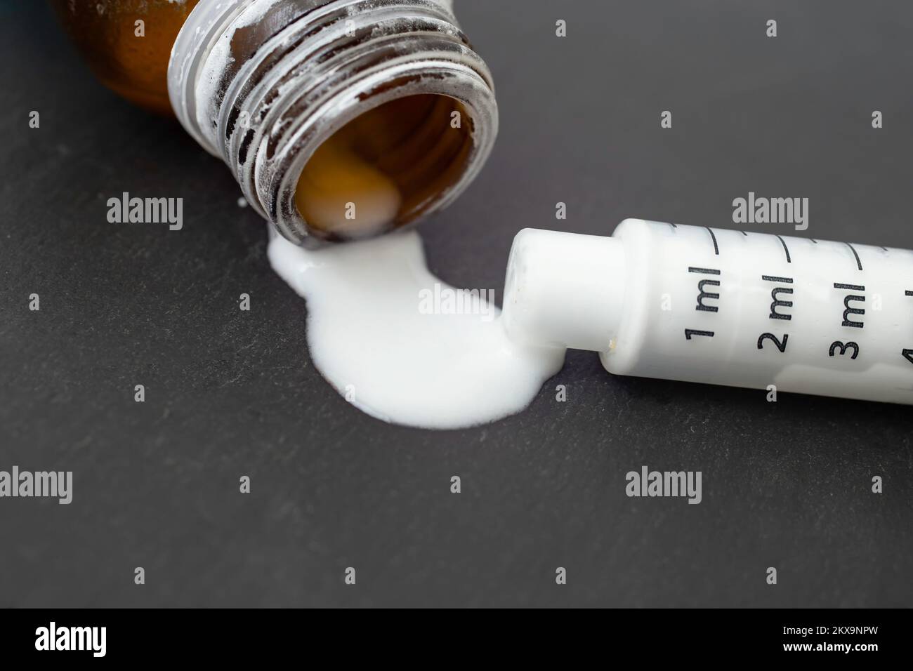 Leere Flasche mit antibiotisch rekonstruierter weißer Substanz mit einer Dosierspritze auf schwarzem Hintergrund, Soft-Focus-Nahaufnahme Stockfoto