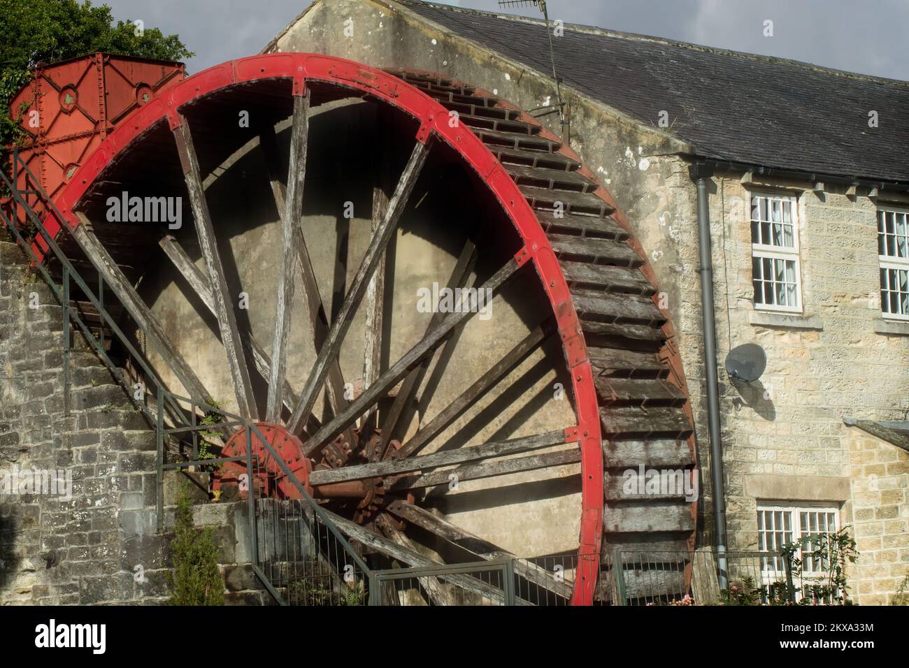 Foster Beck Water Mill in North Yorkshire, Großbritannien, hat ein sofort erkennbares rotes Holzwasserrad an der Seite und ist jetzt ein Wohnblock. Stockfoto