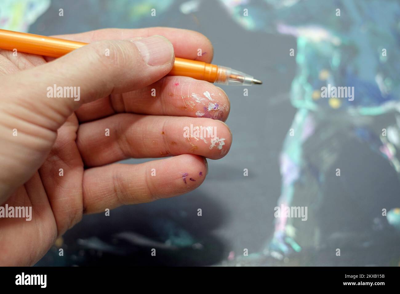 Schmutzige Finger eines Künstlers, der einen Stift hält, Nahaufnahme im Innenbereich Stockfoto