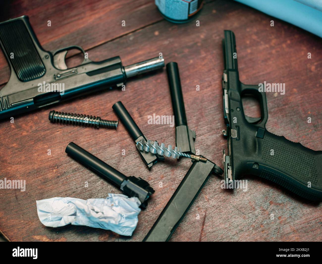 Reinigung und Ölen zerlegter Pistolen auf einem Holztisch, Innenschuss Stockfoto
