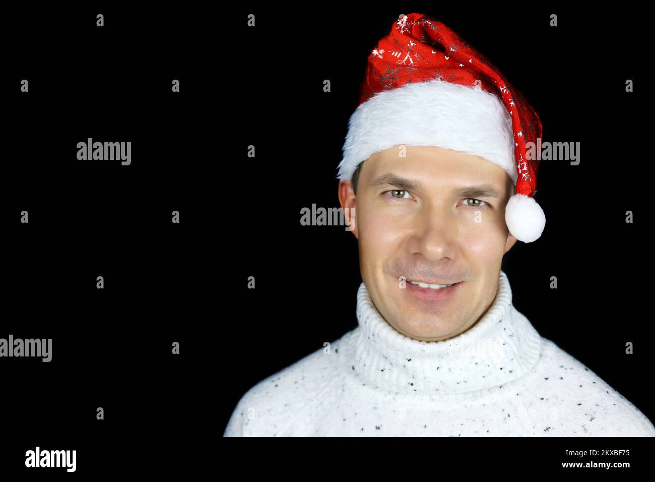 Porträt eines glücklichen Mannes mittleren Alters mit Weihnachtsmannmütze auf schwarzem Hintergrund. Weihnachtsfeier, Neujahrsfeier Stockfoto