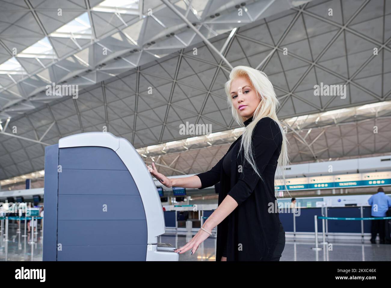 HONGKONG - 02. JUNI 2015: Blonde Frau am Check-in-Automaten. Der Self Check-in-Service bietet die Möglichkeit, Zeit zu sparen und den Check-in zu vermeiden Stockfoto