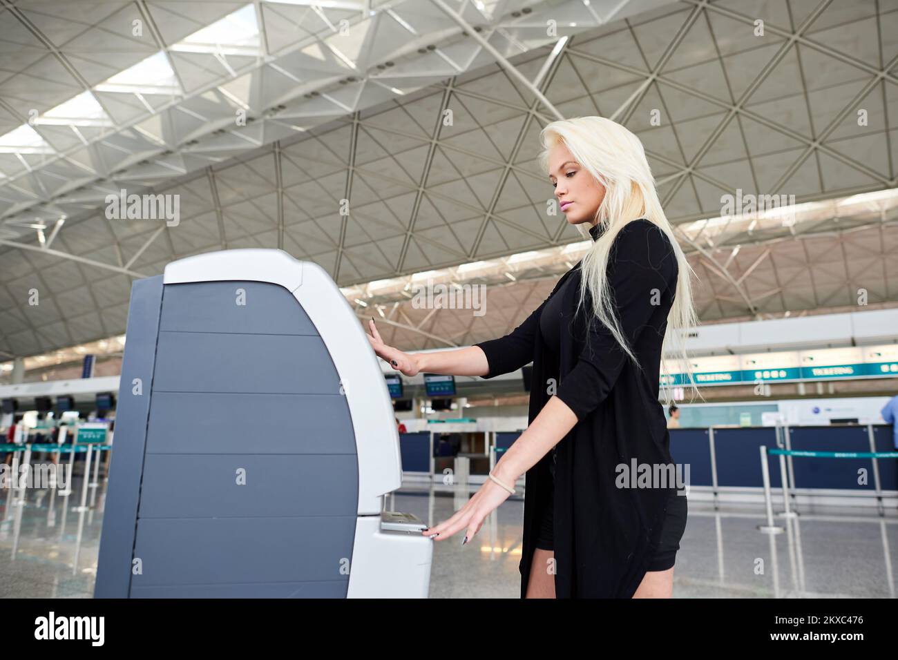 HONGKONG - 02. JUNI 2015: Blonde Frau am Check-in-Automaten. Der Self Check-in-Service bietet die Möglichkeit, Zeit zu sparen und den Check-in zu vermeiden Stockfoto