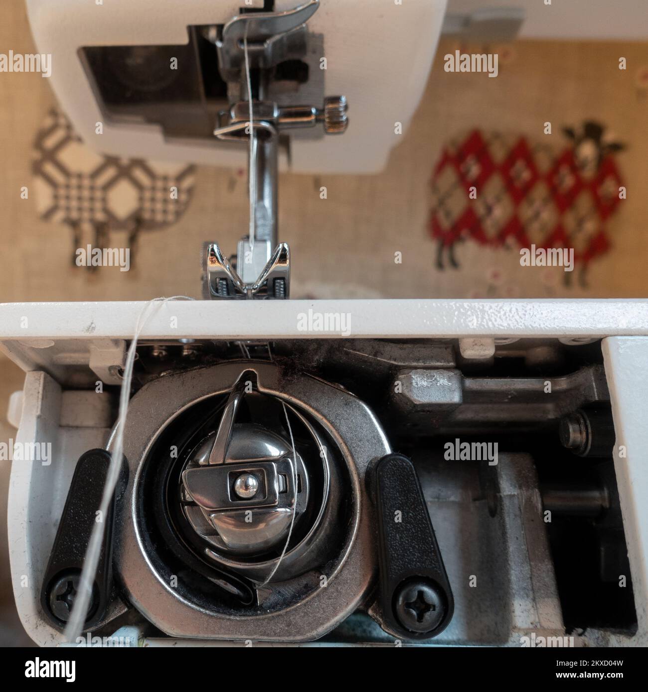 Innenarbeiten einer modernen Nähmaschine, die sich anschaut, wie der Faden unter dem Pressfußteil das Spulengehäuse unten in Großbritannien umschließt Stockfoto