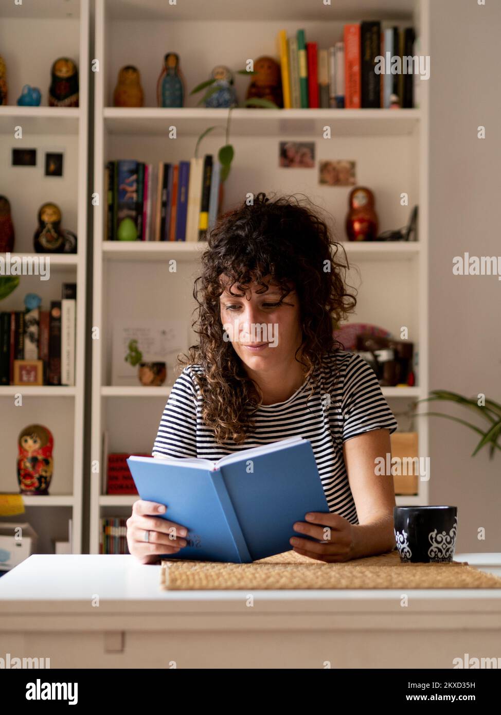 Eine Spanierin liest ein Buch in einer Wohnung Stockfoto