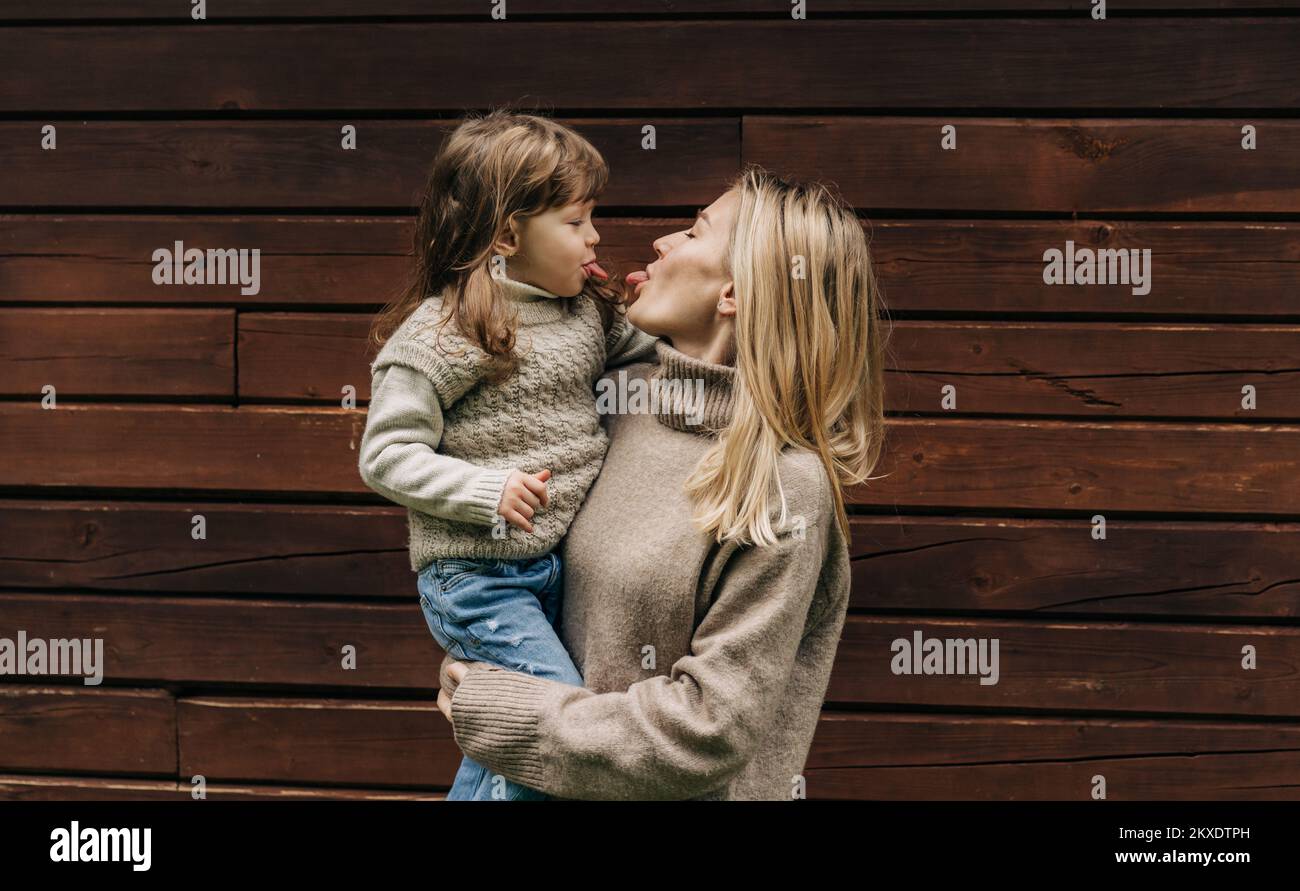 Eine junge Mutter, die eine kleine Tochter in den Armen hält, Mutter und Baby stehen auf Zungen. Stockfoto