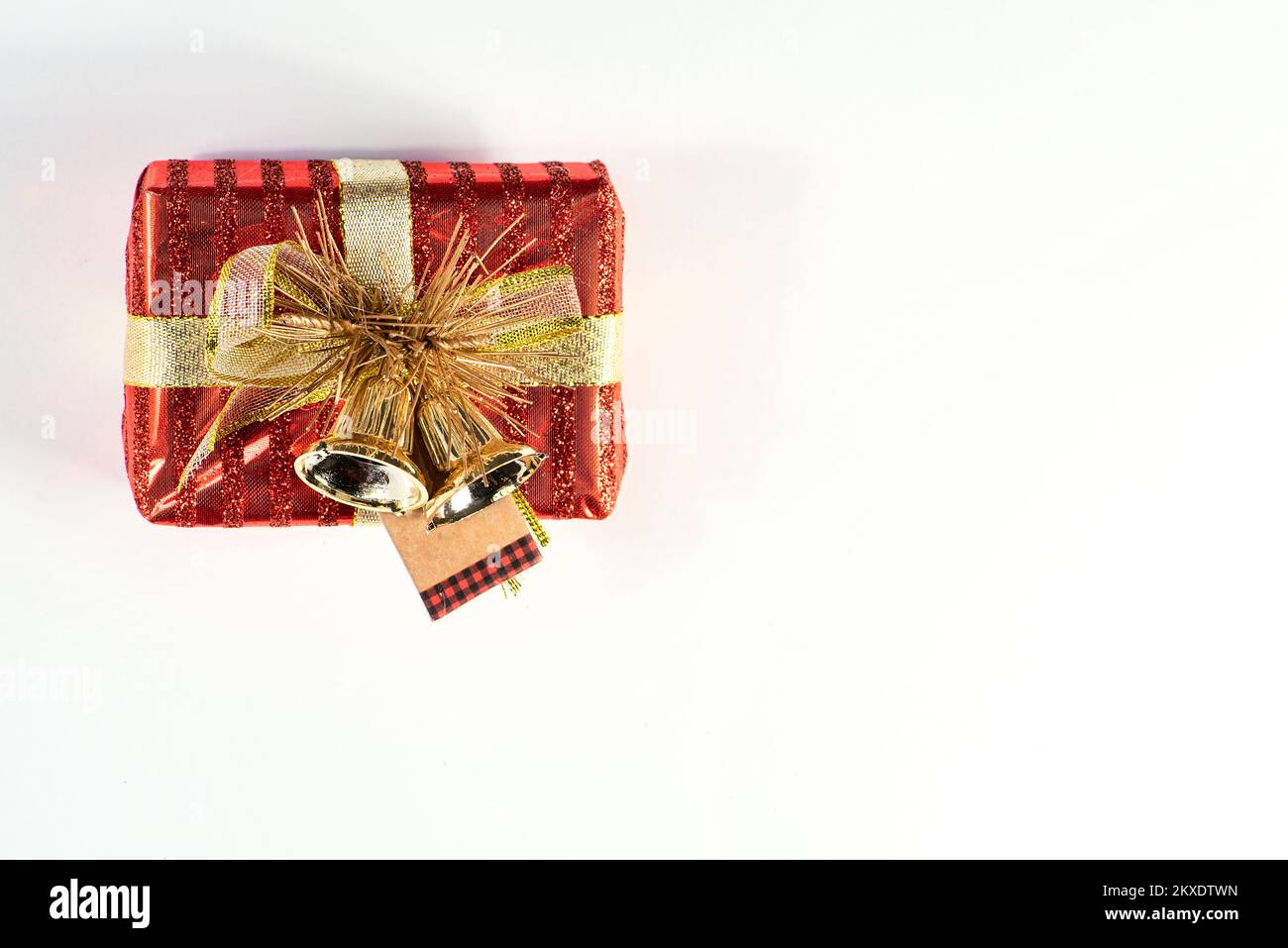 Kleine rote Geschenkbox mit Band und Glocken, Platz für Text auf weißem Hintergrund Stockfoto