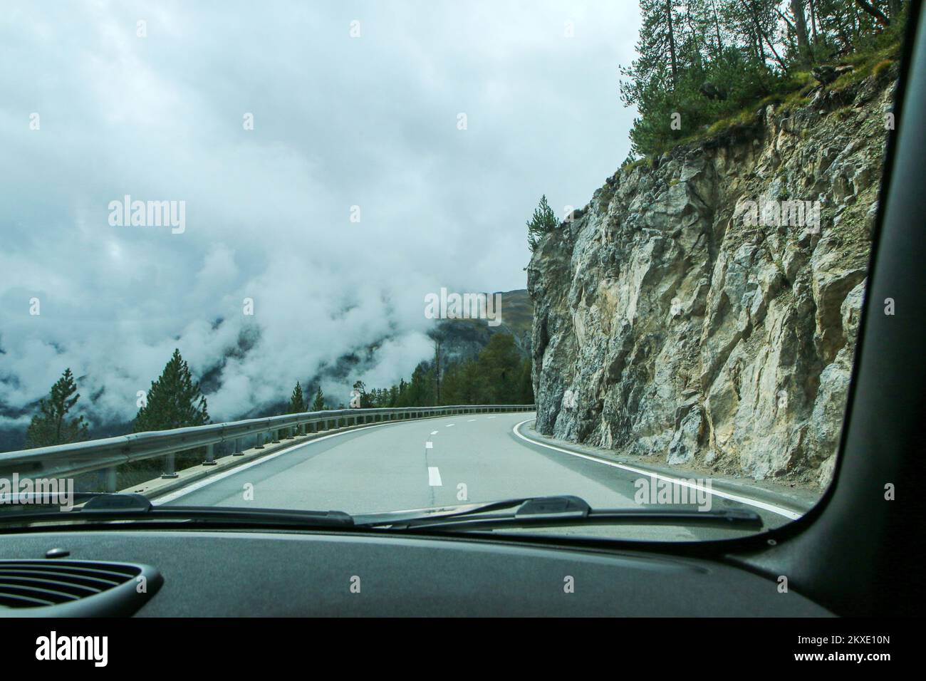 Fahren Sie mit dem Auto auf den alpinen Straßen während des Sommers bewölkt und regnerisch. Die Gipfel sind in den Wolken, die Straßen sind schwierig. Stockfoto