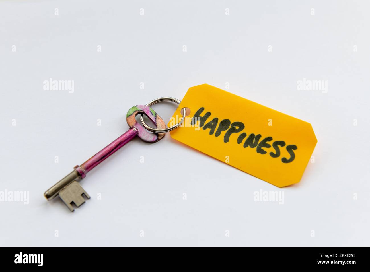 Ein Schlüssel zum Glück Konzept mit einem Schlüssel und dem Wort Glück isoliert auf weißem Hintergrund. Stockfoto