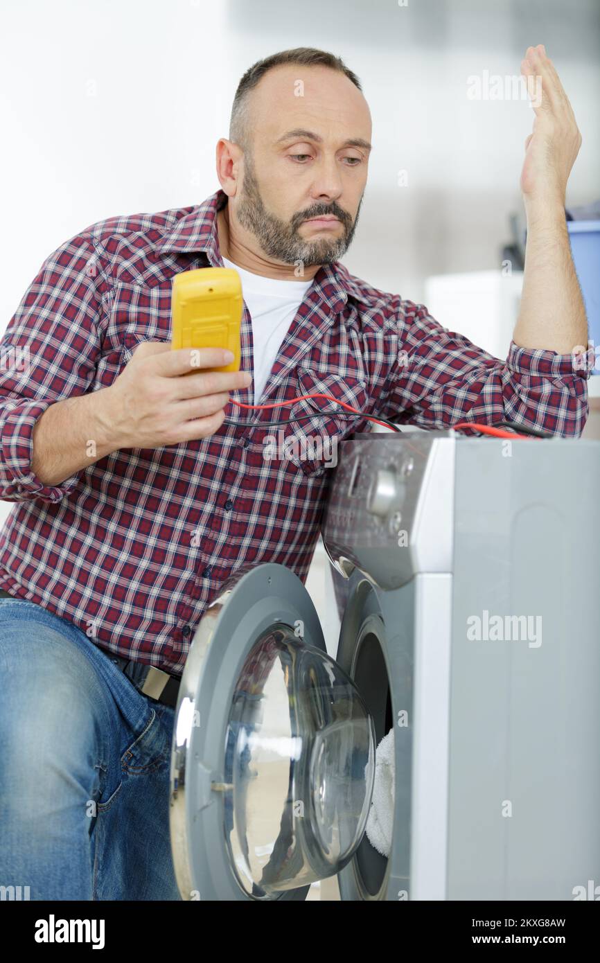 Der Mann repariert ein Problem mit einer Waschmaschine Stockfoto