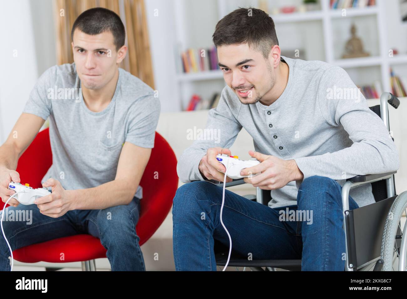 Zwei junge Männer spielen Computerspiel, einer im Rollstuhl Stockfoto