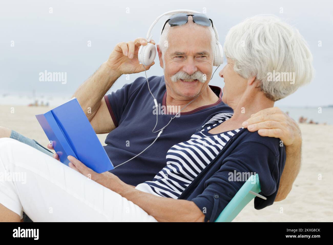 Seniorenpaar steht am Strand und hört mp3-Spieler Stockfoto