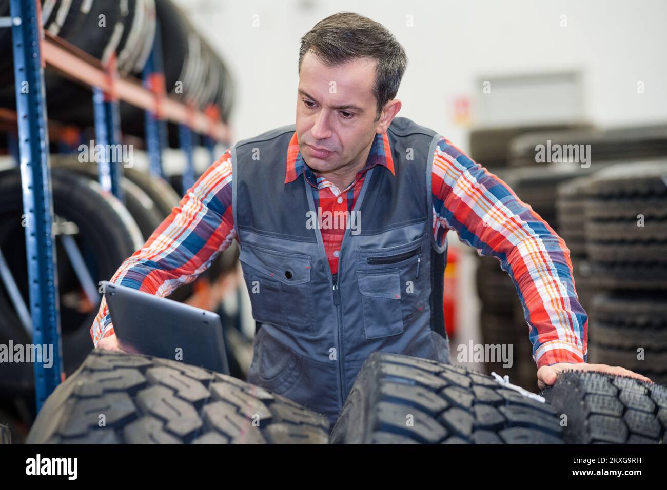 Moderner Mechaniker, der die Reifen mit einem Tablet überprüft Stockfoto