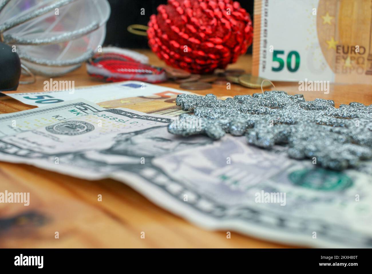 euro-Münzen, Euro- und Dollarscheine und Weihnachtsschmuck auf dem Tisch Stockfoto