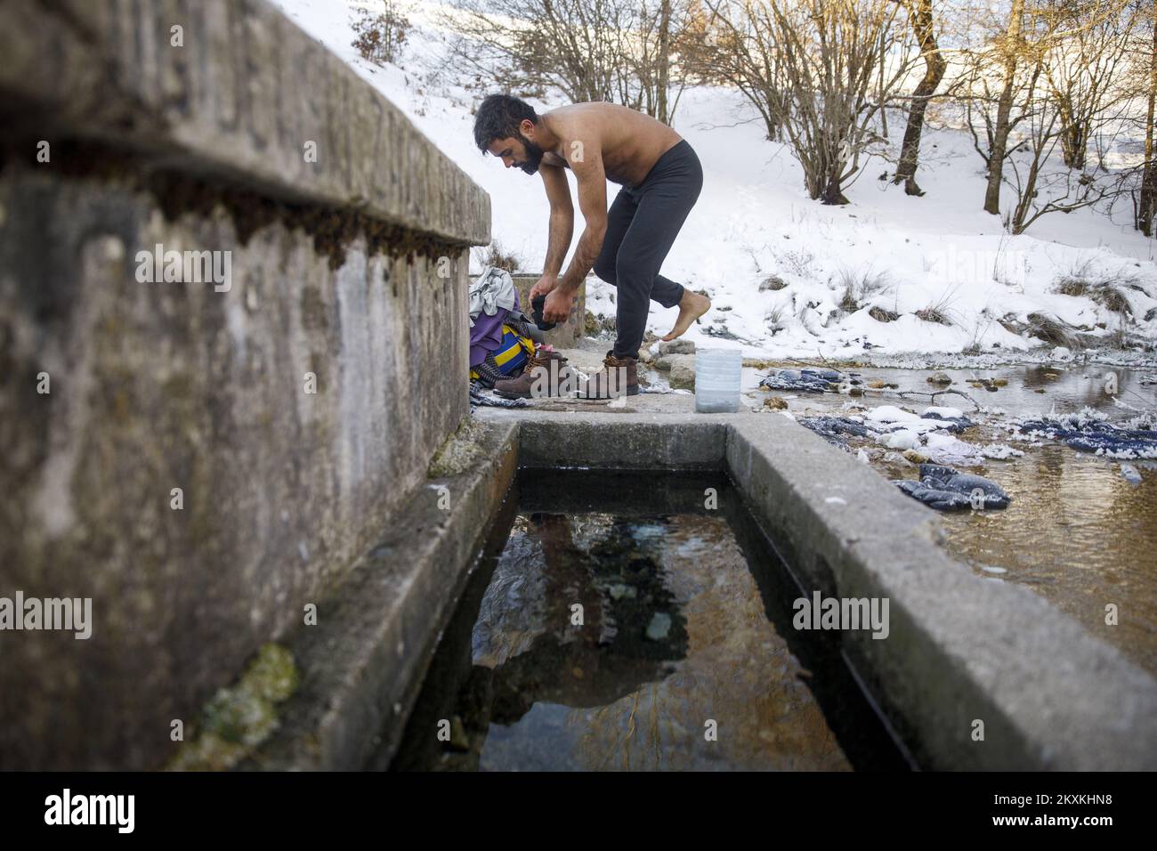 Ein Migrant aus Pakistan, Hagiaz Abdulrehman, reinigt sich am 15. Januar 2021 in einem Bach im Migrantenlager Lipa in der Nähe von Bihac, Bosnien und Herzegowina. Das Wasser in den Tanks ist heute Morgen gefroren, weil die Temperatur um 9 Uhr -14 Grad Celsius betrug. Camp Lipa wird in 3 Monaten voll funktionsfähig sein. Foto: Armin Durgut/PIXSELL Stockfoto