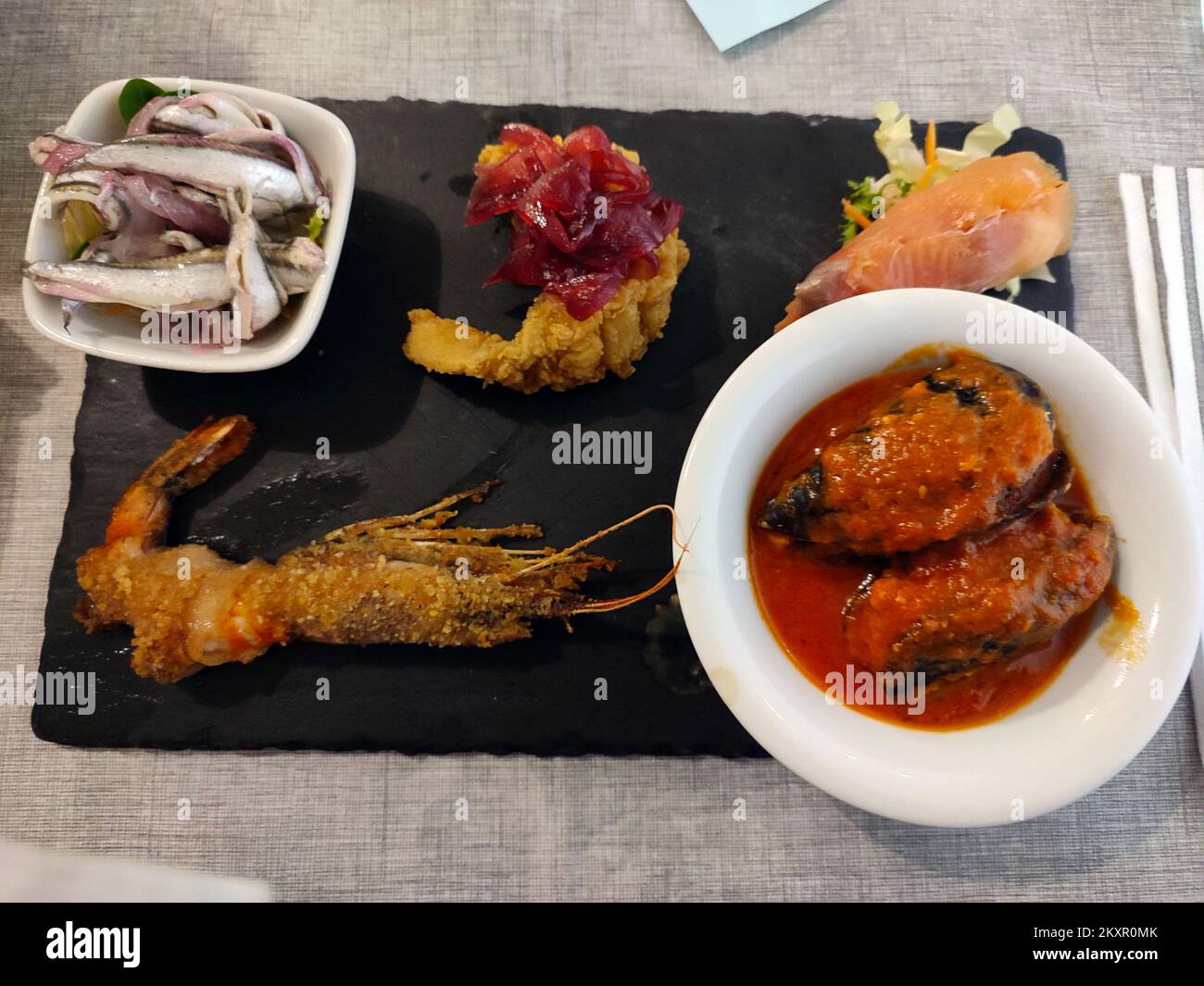 Köstliche Tabletts mit orientalischen Speisen mit Sushi, Garnelen und verschiedenen frittierten Speisen zum Abendessen oder Mittagessen Stockfoto