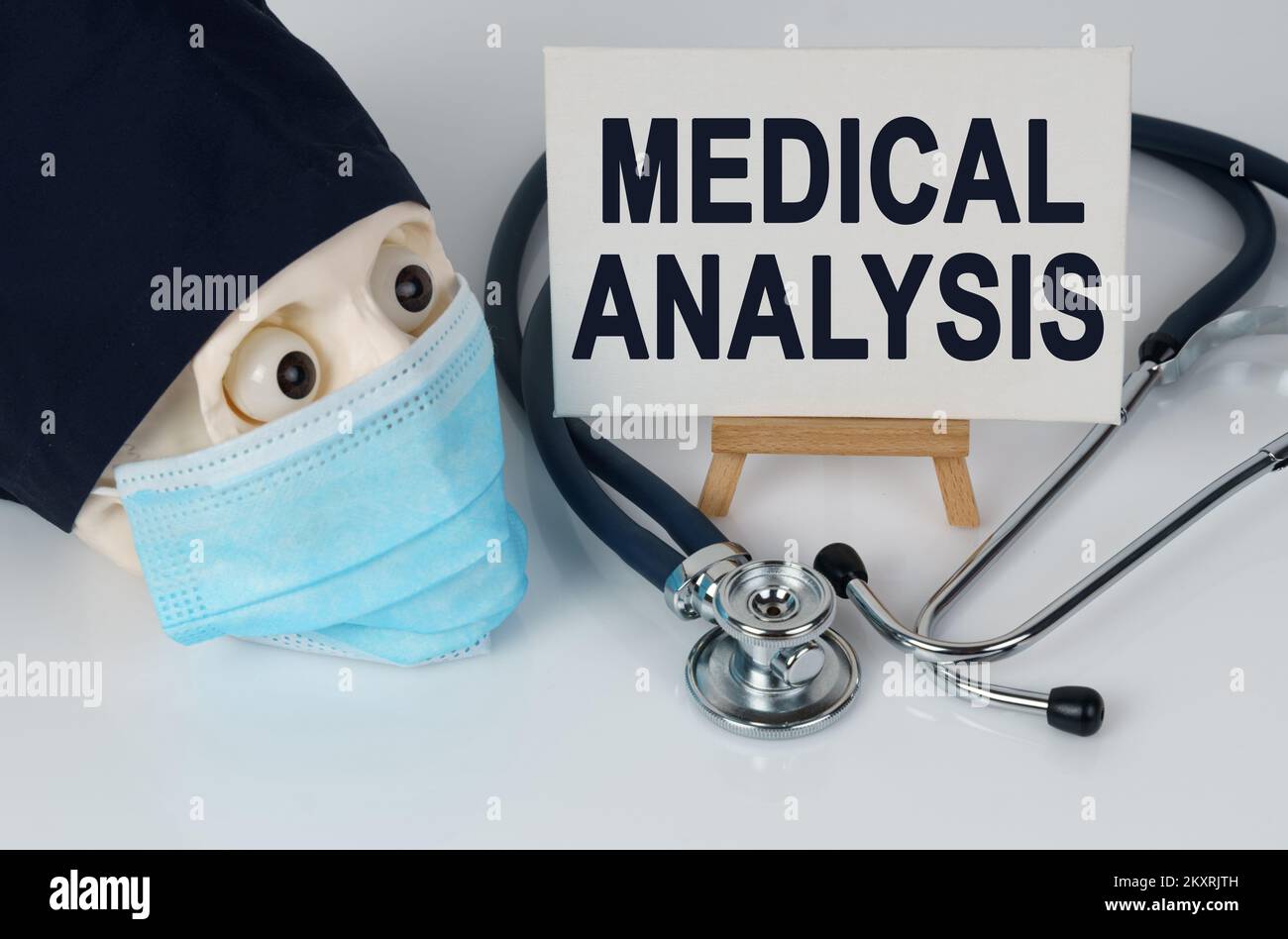 Medizin und Gesundheitskonzept. Schädel in Maske und Kappe, Stethoskop und Staffelei mit Leinwand, auf der es geschrieben ist - MEDIZINISCHE ANALYSE Stockfoto