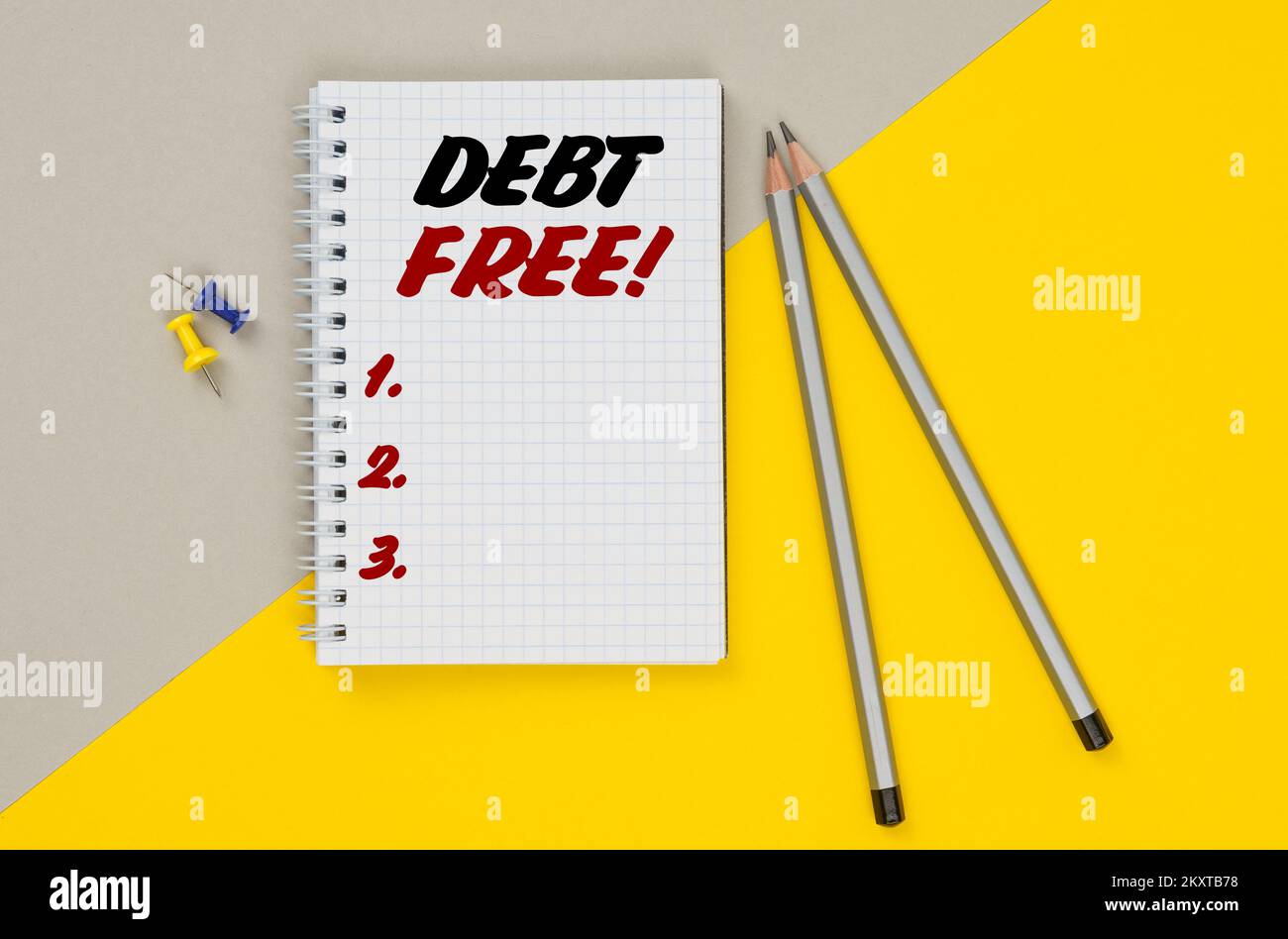 Wirtschaft und Finanzen. Auf einem gelb-grauen Hintergrund sind Bleistifte, Knöpfe und ein Notizbuch, in dem es geschrieben ist - SCHULDENFREI Stockfoto