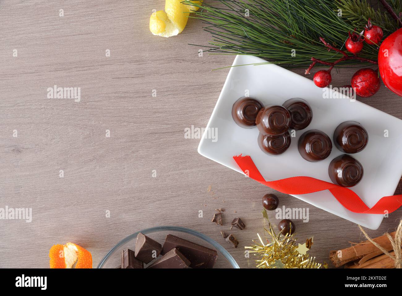 Schokoladenbonbons auf einem rechteckigen Teller auf einem Holztisch mit Weihnachtsdekorationen. Draufsicht. Stockfoto