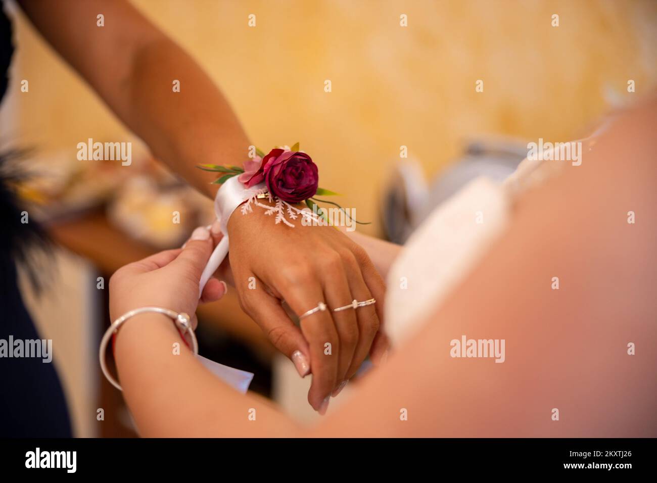 Die Braut legt ihr eine Blumenapplikation auf die Hand ihrer Trauzeugin. Hochwertiges Foto Stockfoto