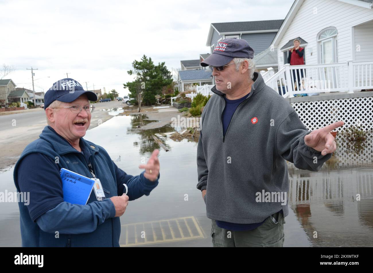Breezy Point, New York, 31. Oktober 2012 Ein Mitarbeiter der FEMA Community Relations spricht mit einem Bewohner von Breezy Point in der Gegend Rockaway in der Nähe von New York City, der aufgrund der Schäden durch den Hurrikan Sandy lokale und staatliche Hilfe benötigt. FEMA Community Relations Mitarbeiter gehen von Haus zu Haus und sprechen mit Bewohnern über die verschiedenen Möglichkeiten, wie FEMA in ihrer Gemeinde ist, um ihnen zu helfen. Walt Jennings/FEMA. Breezy Point, Rockaway, New York. Fotos zu Katastrophen- und Notfallmanagementprogrammen, Aktivitäten und Beamten Stockfoto