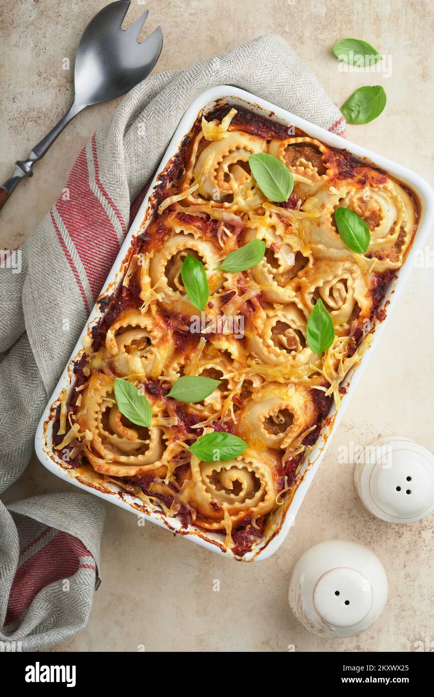 Lasagne. Hausgemachte Lasagne Pasta Rotolo mit Tomatensauce, Frischkäse und Basilikum auf weißer Pfanne auf hellem Schiefer, Stein oder Beton. ICH Stockfoto