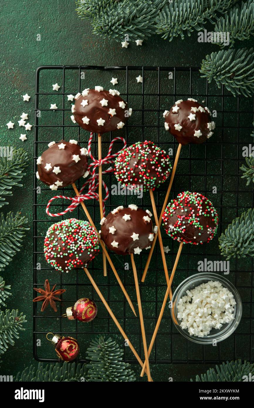 Heirate Weihnachten, süße Kuchenpopps. Weihnachtsdessert runde Brownie-Kuchen mit Sternen auf dunkelgrünem Hintergrund. Weihnachtsessen Dessertkonzept Stockfoto