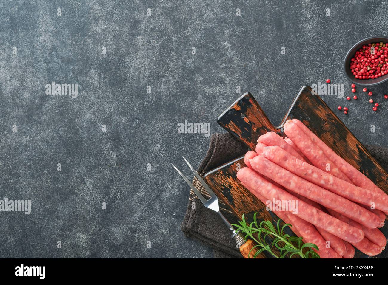 Fleischwurst. Rohe Barbecue-Würste mit Gewürzen, Gemüse und Zutaten zum Kochen auf schwarzem Hintergrund. Draufsicht. Speicherplatz kopieren. Oktoberfest m Stockfoto