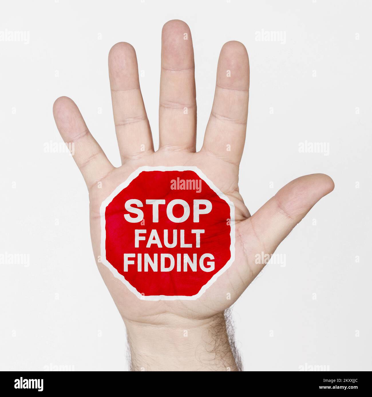 Auf der Handfläche befindet sich ein Stoppschild mit der Aufschrift „STOP FAULT FINDING“. Isoliert auf weißem Hintergrund. Stockfoto