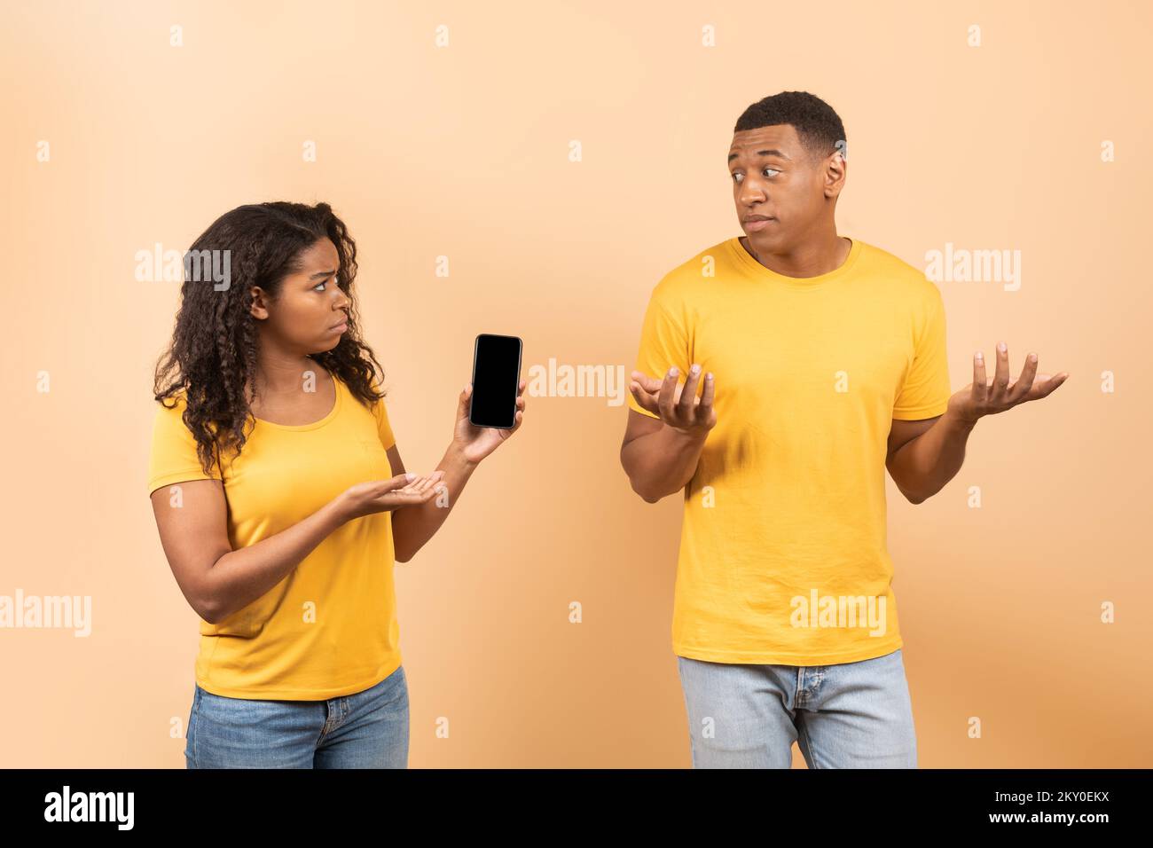 Ein anderes Leben online. Wütende afroamerikanische Dame, die auf dem Handy ihres Mannes nach einer Erklärung fragt Stockfoto