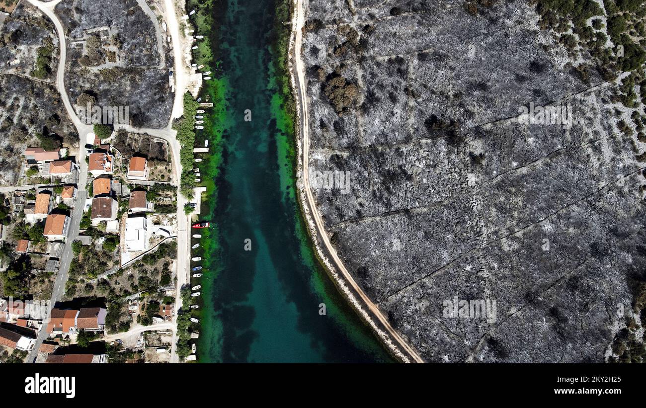 Luftfoto aufgenommen am 19. Juli 2022 zeigt die verbrannte Gegend um Raslina und Zaton in Kroatien. Der Waldbrand, der letzten Mittwoch in den Gebieten Zaton und Raslinje im Bezirk Å ibenik-Knin ausbrach, wurde am Montagmorgen für gelöscht erklärt. Der Brand breitete sich auf schätzungsweise 3.300 Hektar Land aus und verdaute Gras, Unterholz, Holz und landwirtschaftliche Nutzpflanzen. 30 Häuser, mehrere Autos und Boote und drei landwirtschaftliche Maschinen waren im Brandfall niedergebrannt. Foto: Milan Sabic/PIXSELL Stockfoto