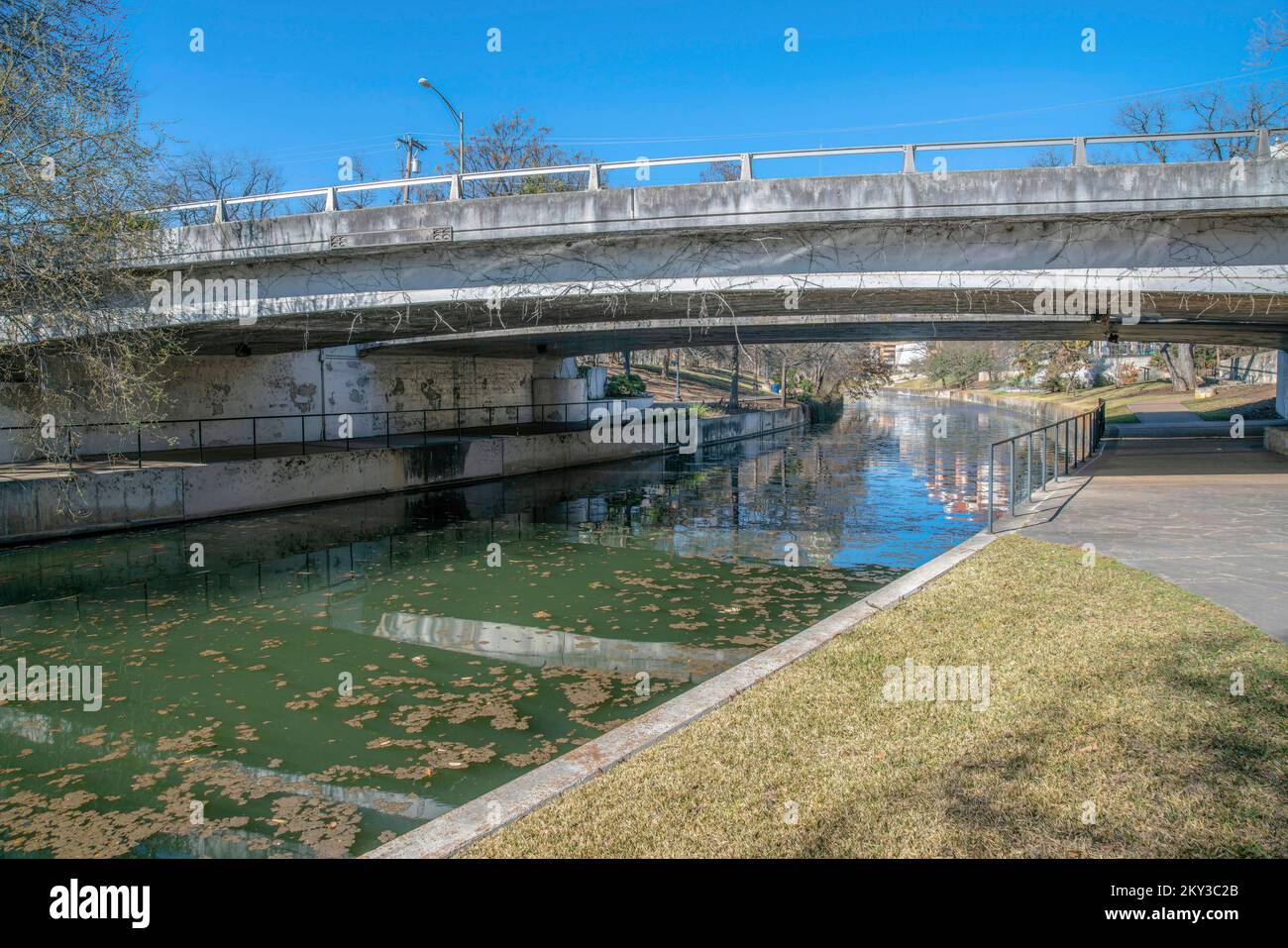 San Antonio River Walk mit Brücke mit Blick auf den malerischen Kanal und den blauen Himmel. Das Wasser wird von gepflasterten Wegen oder Fußwegen für Touristen flankiert, r Stockfoto