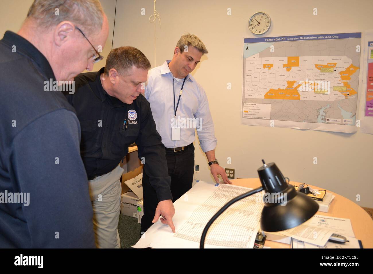 Harrisburg, Pa, 28. Februar 2013 Pennsylvania Emergency Management Agency (PEMA) Commonwealth Coordinating Officer John Forr, FEMA Federal Coordinating Officer Tom McCool und WHP-TV 21 CBS Chief Meteorologe Tom Russell diskutieren Wiederaufbaumaßnahmen in der PEMA-FEMA-Außenstelle in Harrisburg. Russell besuchte das gemeinsame Informationszentrum, um eine 30-sekündige Ankündigung des öffentlichen Dienstes für Radio zur Unterstützung der National Severe Weather Preparedness Week aufzuzeichnen. Pennsylvania, schwere Stürme und Überschwemmungen. Fotos zu Katastrophen- und Notfallmanagementprogrammen, Aktivitäten und Beamten Stockfoto