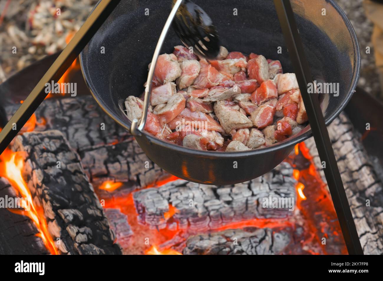 Fleischstücke in einem Kessel. Camping Kochen. Holzfeuer und Kessel mit Essen. Street Food. Essen auf dem Feuer. Ich koche Fleisch in einem Kessel. Stockfoto