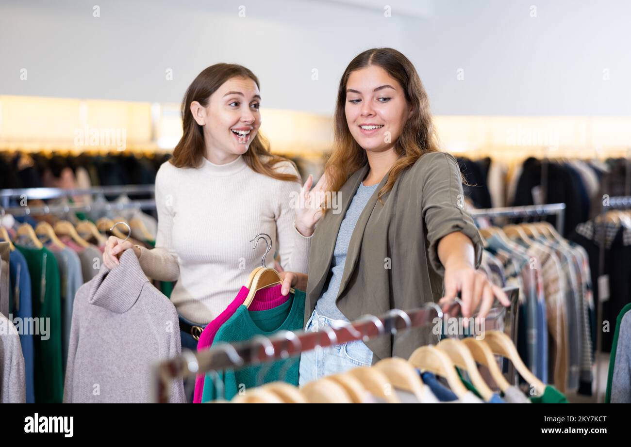 Einkaufsraum des Bekleidungsgeschäfts mit jungen Frauen, die Jacken und Pullover aussuchen Stockfoto