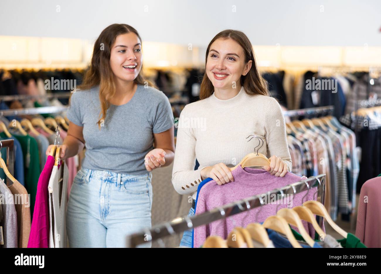 Einkaufsraum des Bekleidungsgeschäfts mit jungen Frauen, die Jacken und Pullover aussuchen Stockfoto