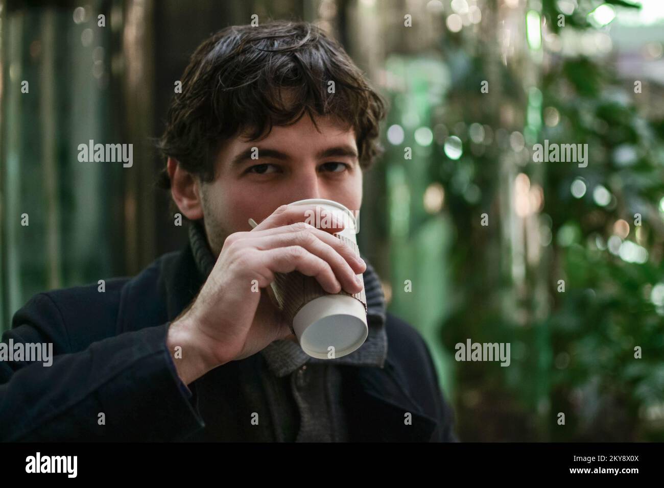 Junger, gutaussehender Mann, der Kaffee trinkt und in die Kamera schaut Stockfoto