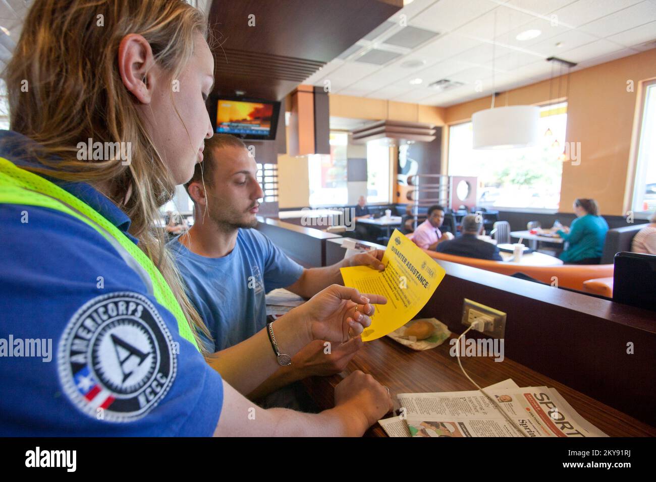 Pensacola, Florida, 15. Mai 2014 Mitglied des FEMA Corps, Marie Orechoff liefert Katastropheninformationen für einen Katastrophenüberlebenden in einem lokalen Restaurant. Orechoff ist Mitglied des Disaster Survivor Assistance Team (DSAT) der FEMA und wurde nach einer Überschwemmung in der Region nach Pensacola entsandt. Andrea Booher/FEMA. Schwere Stürme, Tornados, Stürme und Überschwemmungen in Florida. Fotos zu Katastrophen- und Notfallmanagementprogrammen, Aktivitäten und Beamten Stockfoto