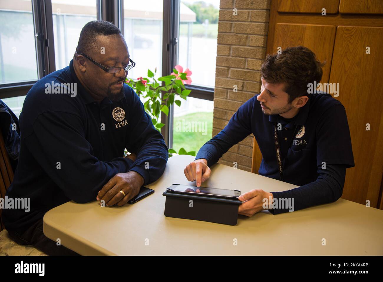 Warren, MI, 5. Oktober 2014 – Mark L. Johnson (links), FEMA Disaster Survivor Assistance (DSA) Specialist und Dustin Hendrikse (rechts), DSA Cred Lead, prüfen die Zuweisung eines Katastrophenüberlebenden und zugehöriges Material auf einer Recovery Support Site (RSS) im Besucherraum der Warren First United Methodist Church in Warren, Michigan Nachdem die Detroit Metropolitan Counties Oakland, Wayne und Macomb vom 11. Bis 13. August 2014 von schweren Stürmen und Überschwemmungen betroffen waren. Die FEMA unterstützt lokale und staatliche Regierungen und Stammeseinheiten bei ihren Bemühungen, sich von Naturkatastrophen zu erholen. Michigan Se Stockfoto