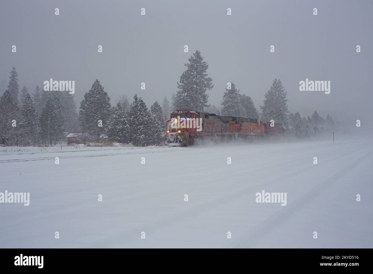 Eine BNSF GE C44-9W dieselelektrische Lokomotive, die einen Güterzug mit Öltankern fährt, die die Gleise in Troy, Montana, entlangfahren. Stockfoto