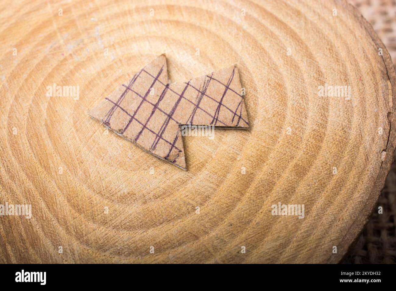 Pfeil-Symbol auf Stück Holz aus braunem Papier schneiden Stockfoto