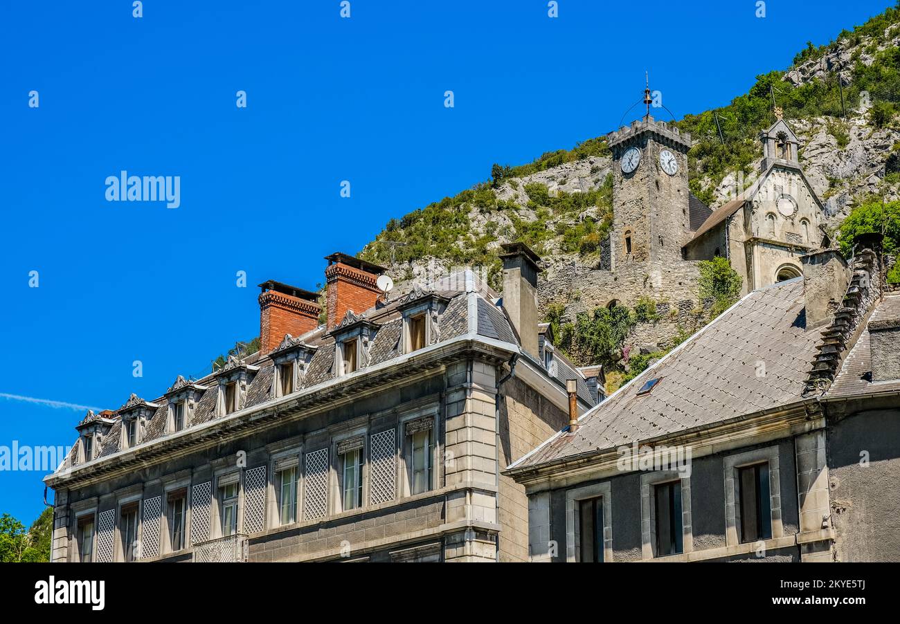 Blick auf das alte Schloss Saint Beat Lez, jetzt Ruinen mit nur noch einer Kapelle und einem Uhrenturm und die Dächer dieser kleinen Stadt im Süden Frankreichs (Haute GA Stockfoto