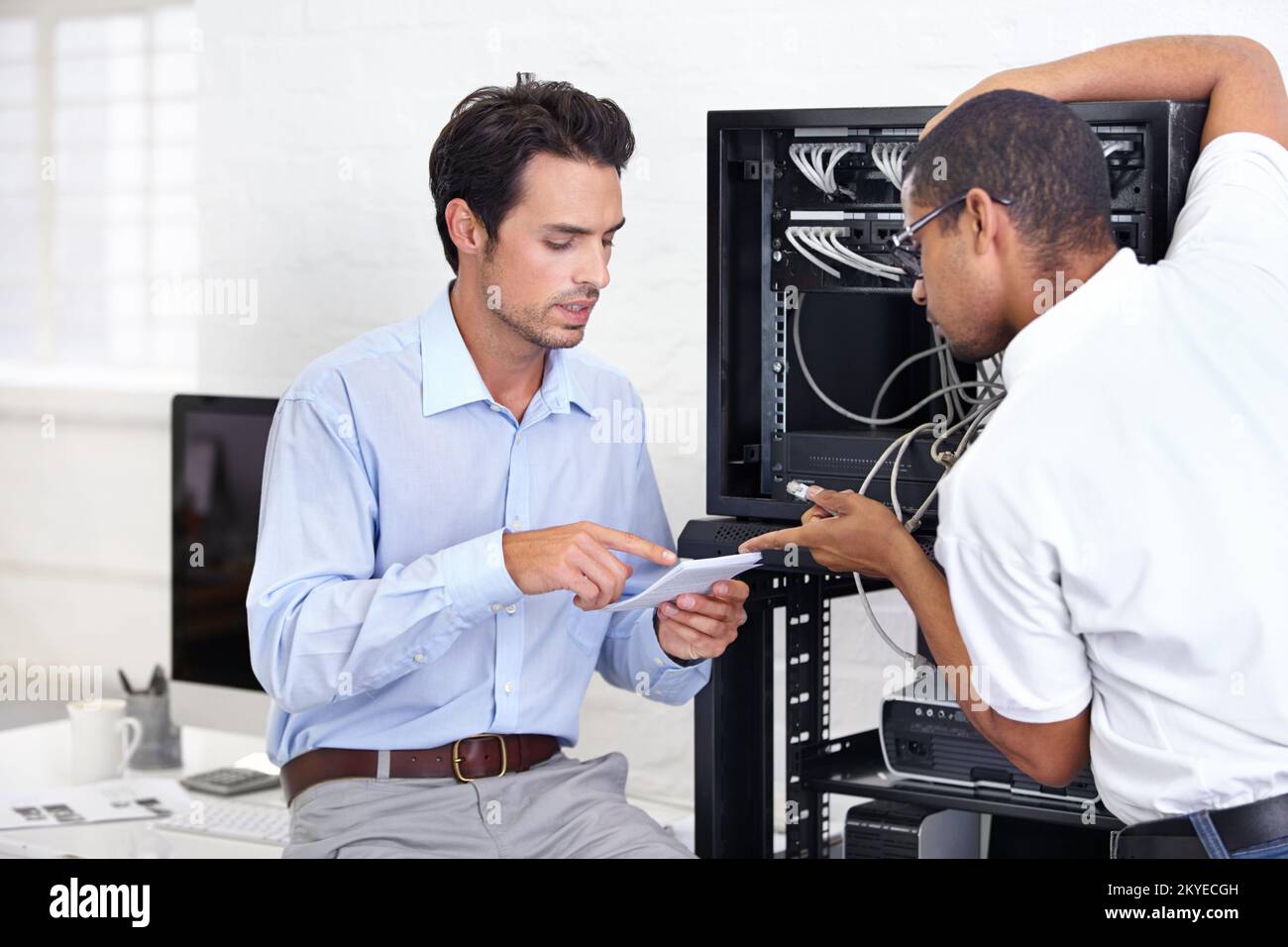 Im Handbuch steht... Ein junger IT-Spezialist, der bereit ist, einen Server zu reparieren. Stockfoto