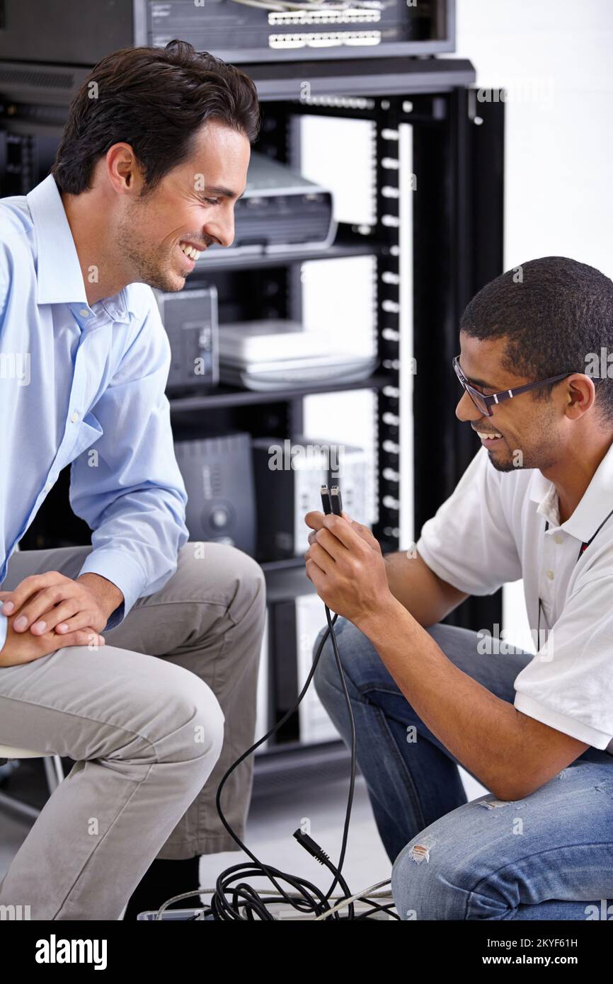 Hier ist das Kabel, nach dem wir gesucht haben. Zwei IT-Profis, die nach der Lösung eines Problems lächeln. Stockfoto
