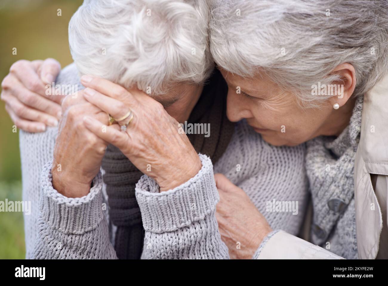 Ich bin hier, um dir die Tränen zu wischen... eine ältere Frau, die ihre Freundin tröstet, während sie draußen sitzt. Stockfoto