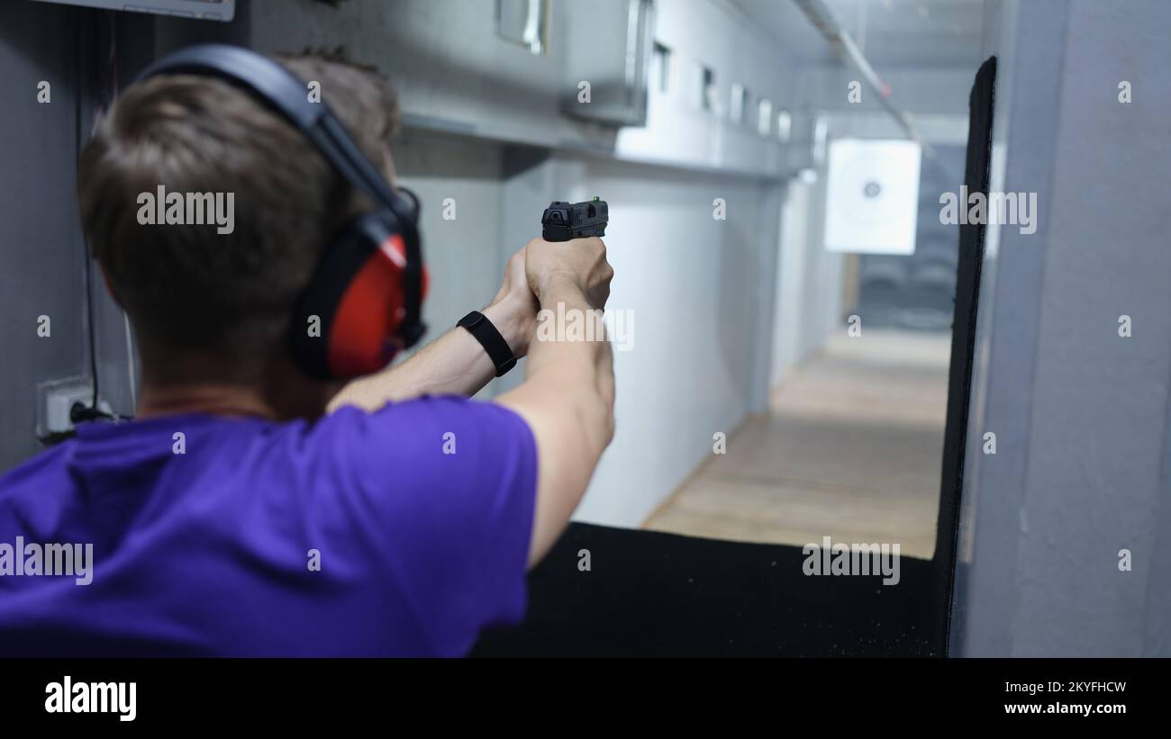 Ein Mann schießt auf das Ziel mit einer Pistole im Schießstand. Stockfoto