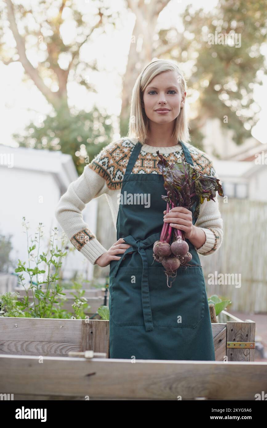 Es war eine üppige Saison. Eine junge Frau steht in einem Garten mit frischer Rote Bete. Stockfoto