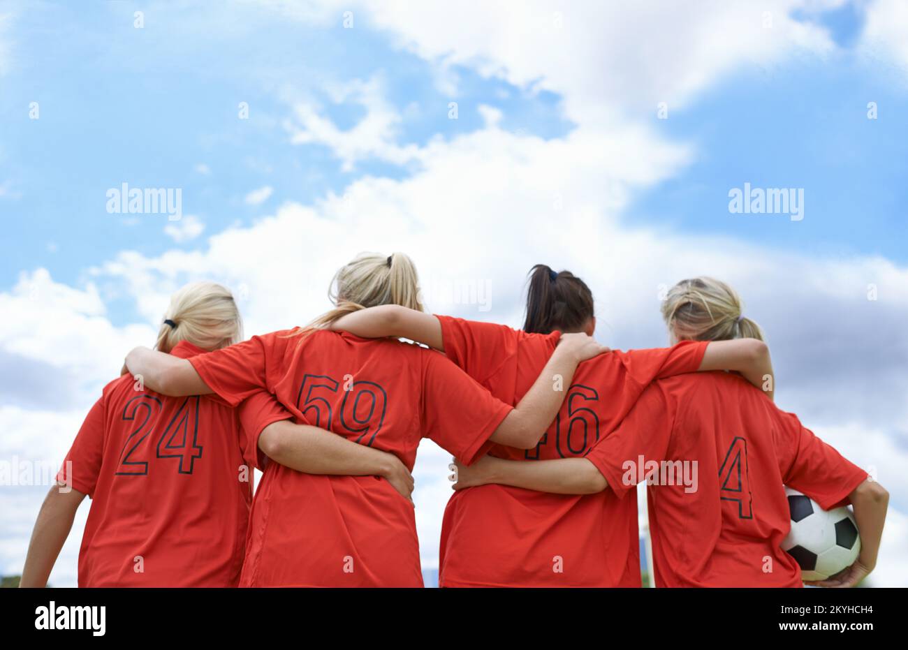 Ich bereite mich auf das Spiel vor. Ein Mädchen-Fußballteam, das mit den Armen um die Schultern steht und auf das Spielfeld blickt. Stockfoto