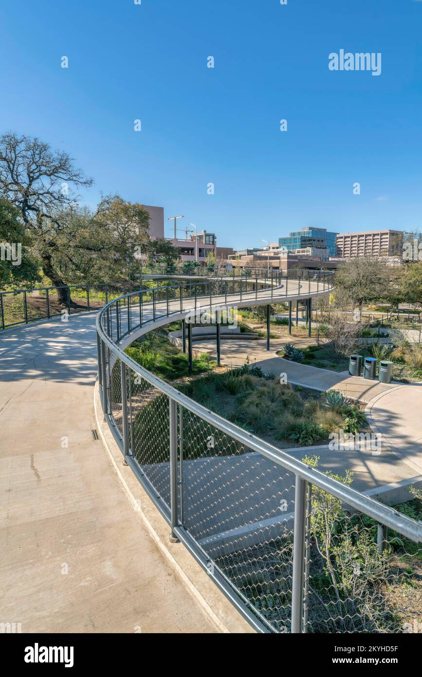 Austin, Texas – Fußgängerbrücke mit Blick auf die Wege und Gebäude im Waterloo Park. Brücke mit Betonpflaster und Kettenschloss-Absperrung Stockfoto